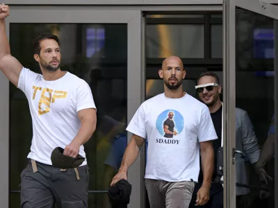 FILE - Andrew Tate, center, and his brother Tristan, left, exit the Bucharest Tribunal after being placed under house arrest, in Bucharest, Romania, Aug. 22, 2024. (AP Photo/Alexandru Dobre, File)