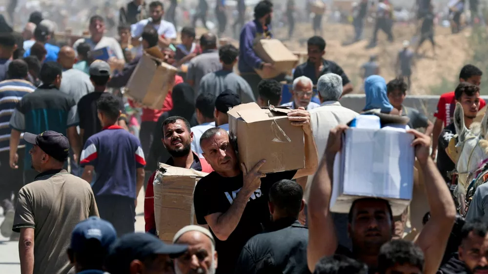 Palestinians carry aid supplies which they received from the U.S.-backed Gaza Humanitarian Foundation, in the central Gaza Strip, May 29, 2025. REUTERS/Ramadan Abed REFILE - CORRECTING LOCATION FROM "NEAR AN AREA OF GAZA KNOWN AS THE NETZARIM CORRIDOR" TO "IN THE CENTRAL GAZA STRIP".