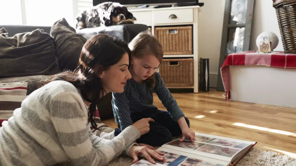 Mother And Daughter At Home Looking Through Photo Album
