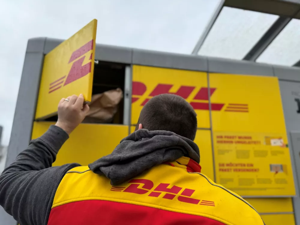FILED - 02 December 2024, North Rhine-Westphalia, Duesseldorf: A DHL parcel carrier stands at a Packstation to fill it with parcels. Photo: Wolf von Dewitz/dpa-Zentralbild/dpa