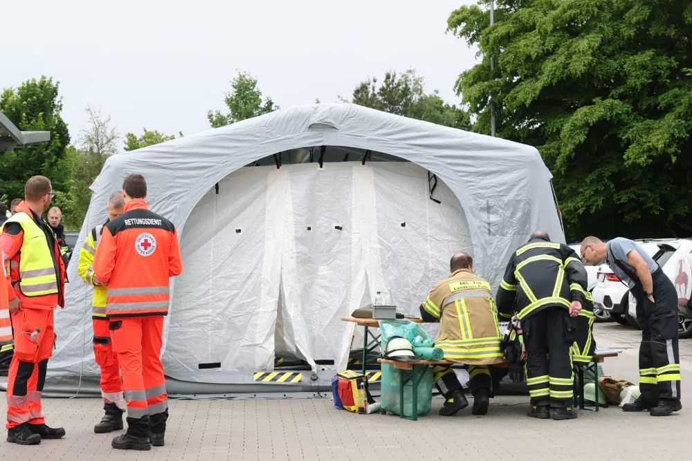 06 June 2025, Bavaria, Langenzenn: Rescue workers stand on the premises of a DHL distribution center in Langenzenn near Nuremberg. Twelve employees have suffered skin injuries at a distribution center of the logistics company DHL. At least eight of them are receiving dermatological treatment, a police spokeswoman said. The distribution center was evacuated as a precaution. "There was no danger to the public," she emphasized. The background was initially unclear. Photo: Daniel Karmann/dpa
