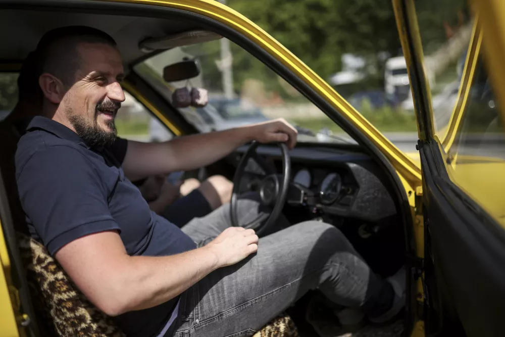 Tarik Fatic sits down in the Reliant Regal, an exact copy of the famous BBC TV show  "Only Fools and Horses" iconic yellow car in Hadzici, suburb of Sarajevo, Bosnia, Wednesday, June 4, 2025. (AP Photo/Armin Durgut)