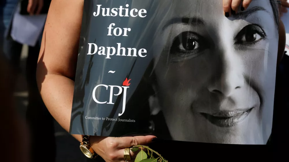A person holds a placard depicting Daphne Caruana Galizia, prepared by Committee to Protect Journalists (CPJ), as people gather at the site where anti-corruption journalist was assassinated in a car bomb one year ago, in Bidnija, Malta October 16, 2018. REUTERS/Darrin Zammit Lupi - RC16E46980D0