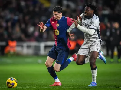 27 March 2025, Spain, Barcelona: Barcelona's Robert Lewandowski and Osasuna's Enzo Boyomo battle for the ball during the Spanish La Liga soccer match between Real Madrid and CA Osasuna at Estadi Olimpic Lluis Companys. Photo: Matthieu Mirville/ZUMA Press Wire/dpa