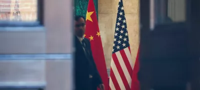 A man stands next to U.S. and China flags at Lancaster House, on the second day scheduled for trade talks between the U.S. and China, in London, Britain, June 10, 2025. REUTERS/Toby Melville