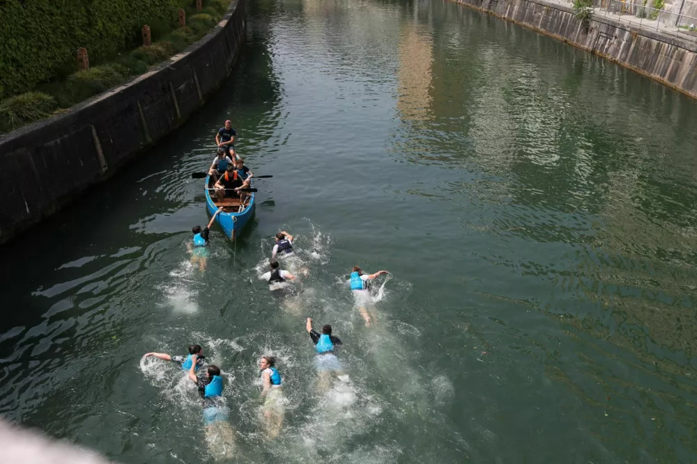 11.06.2025. Skupina mladeničev skače v Ljubljanico s Tromostovja. Vročinski val. Foto: Bojan Velikonja 