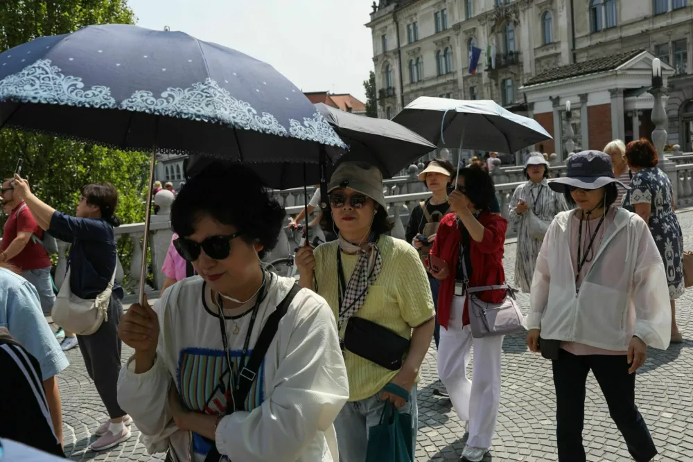 11.06.2025. Azijski turisti s senčniki v Ljubljani. Vročinski val. Foto: Bojan Velikonja 