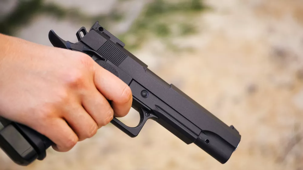 Realistic black airsoft gun in person hand. Close-up