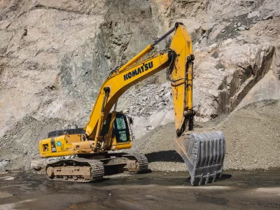 Komatsu PC300 yellow excavator in Almaty mountains, rock formation on the background. Almaty, Kazakhstan - September 28, 2022