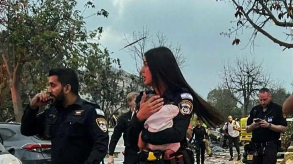 Policistka v rokah drži rešenega otroka.