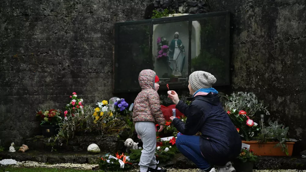 ﻿Denise Gormley and her daughter Rosa, 7, pay their respects and blow bubbles at the Tuam graveyard, where the bodies of 796 babies were uncovered at the site of a former Catholic home for unmarried mothers and their children, on the day a government-ordered inquiry into former Church-run homes for unmarried mothers is formally published, in Tuam, Ireland, January 12, 2021. REUTERS/Clodagh Kilcoyne