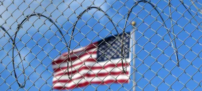 FILED - 15 January 2023, Cuba, Guant?namo: A U.S. flag flies behind barbed wire at the Guant?namo Bay naval base in Cuba. The US government flew 177 deportees from Guantanamo Bay to Honduras on 20 February. US border protection agency ICE said the deportees were then picked up and returned home by the Venezuelan government. Photo: Magdalena Miriam Tr?ndle/dpa