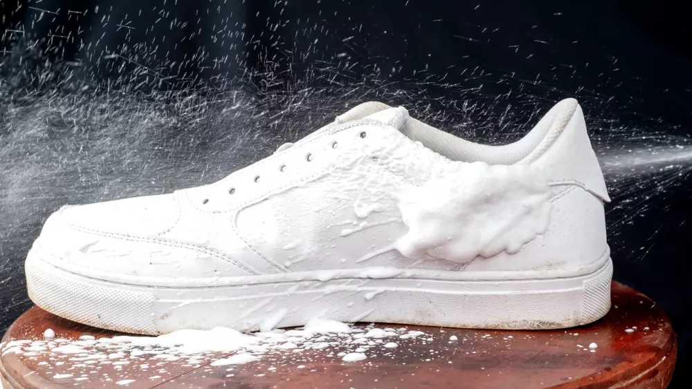 White leather shoes sprayed with cleaning foam. Caring for leather footwear.