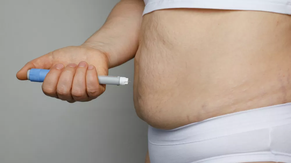 Weight Loss concept. Woman with Semaglutide Injection Pen and her Stomach closeup indoor / Foto: Jnemchinova
