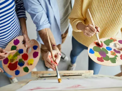 Overview of man with paintbrush teaching his students with color palette how to paint professionally / Foto: Seventyfour