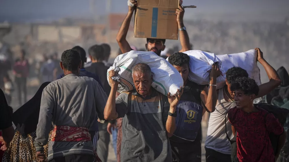 Palestinians carry sacks and boxes of food and humanitarian aid unloaded from a World Food Program convoy that had been heading to Gaza City, in the northern Gaza Strip, Monday, June 16, 2025. (AP Photo/Jehad Alshrafi)