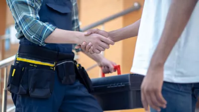 Cropped photo of a repairman holding a toolbox while shaking hands with his client outdoors / Foto: Oleksandr But