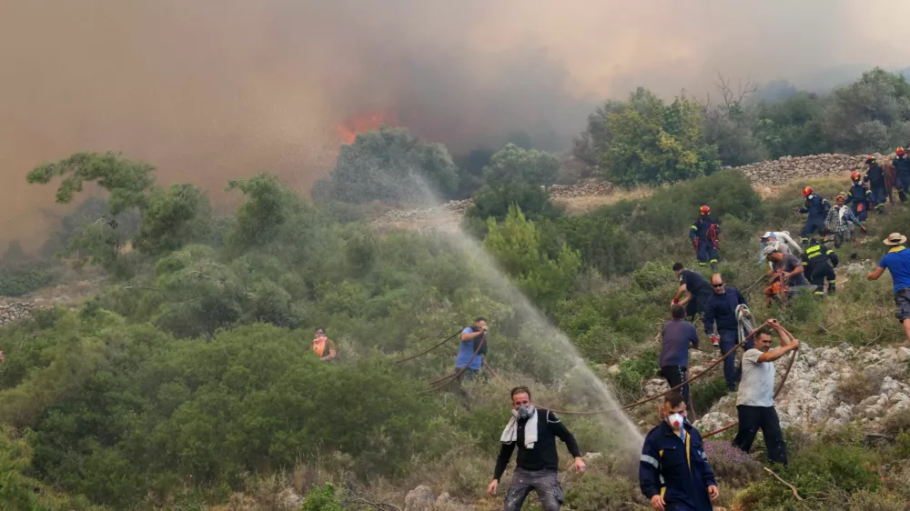 Firefighters and volunteers try to tackle a wildfire burning near the village of Agios Georgios Sikousis, on Chios island, Greece, June 23, 2025. REUTERS/Konstantinos Anagnostou