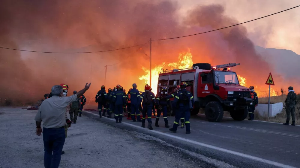 Firemen work to extinguish a wildfire, fanned by strong winds, which led to evacuation messages for villages, near the village of Karyes on Chios island, Greece, June 22, 2025. REUTERS/Konstantinos Anagnostou   TPX IMAGES OF THE DAY