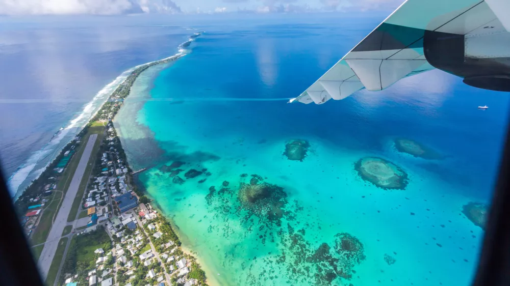 Tuvalu under the wing of an airplane. Aerial view of Funafuti atoll and the airstrip of International airport in Vaiaku. Fongafale motu. Island nation in Polynesia, South Pacific Ocean, Oceania.