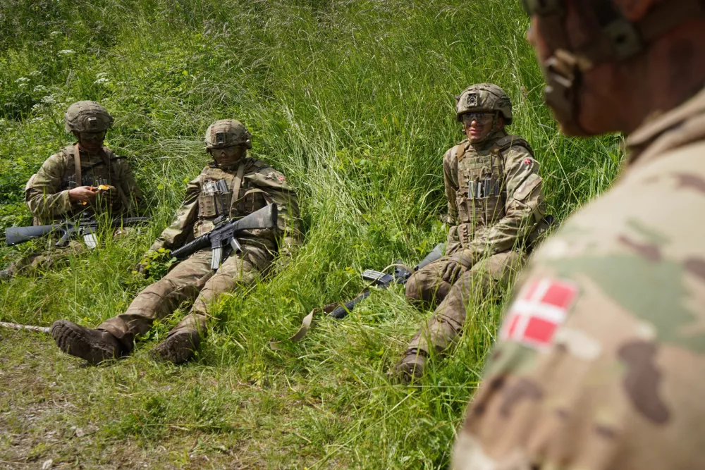 Young conscripts sit waiting in the grass during final exercises at a training area close to Royal Danish Army's barracks in Hovelte, 25 kilometres north of Copenhagen, Denmark, Wednesday, June 11, 2025. (AP Photo/James Brooks)