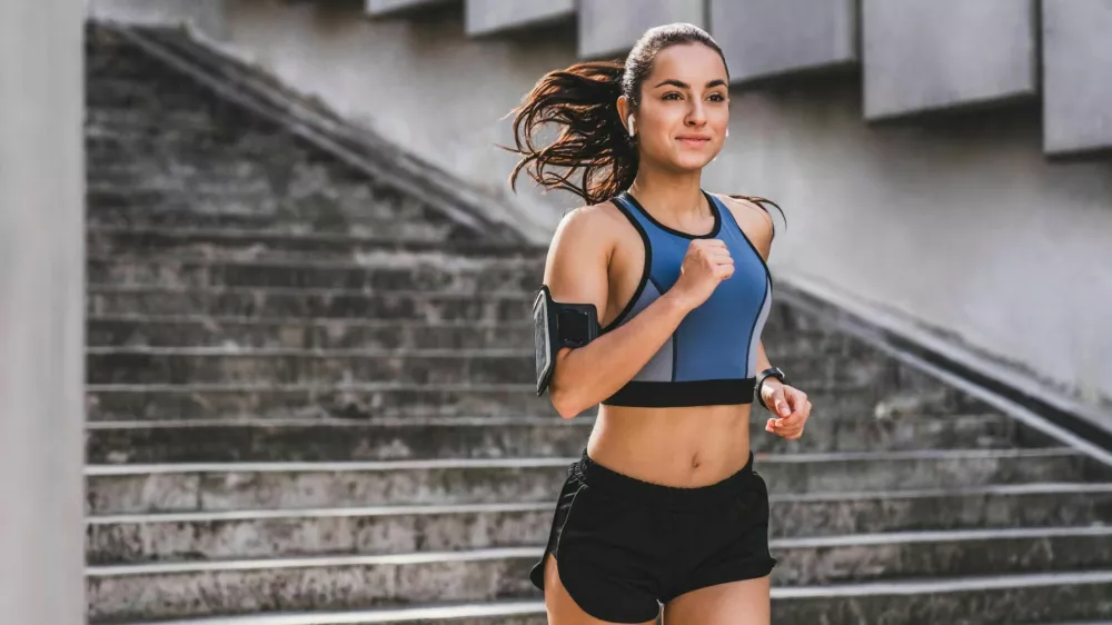 Young caucasian woman runner jogging on the stairs in sporty outfit outdoors / Foto: Inside Creative House