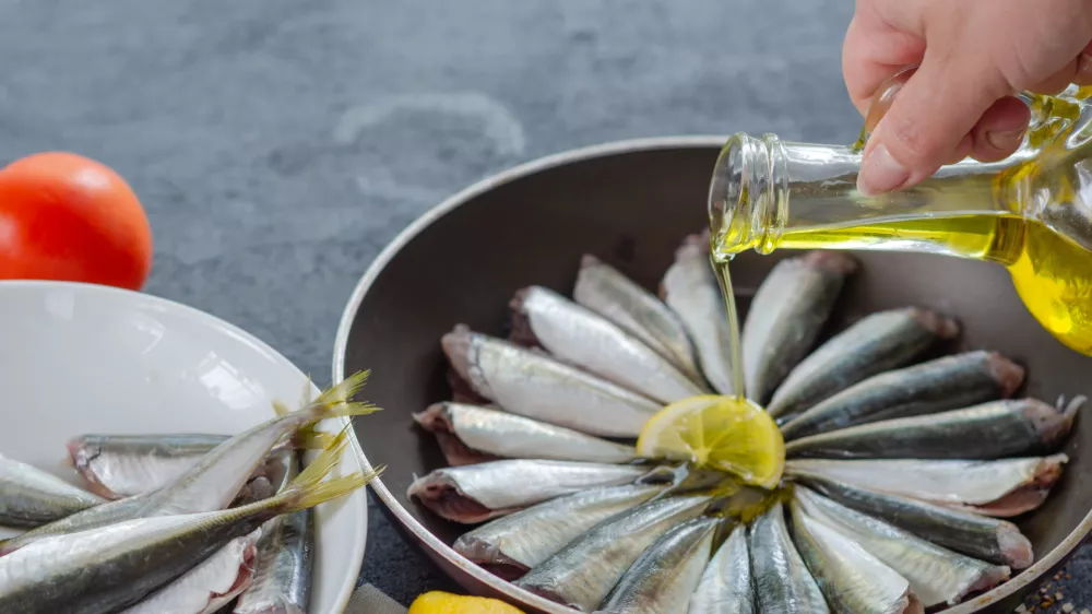 Woman is pouring olive oil into the pan. / Foto: Nkeskin