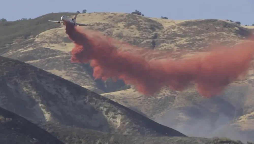 In this image taken from video shows a plane dropping fire retardant the Madre Fire in southeastern San Luis Obispo County, central Calif., July 2, 2025. (KEYT via AP)