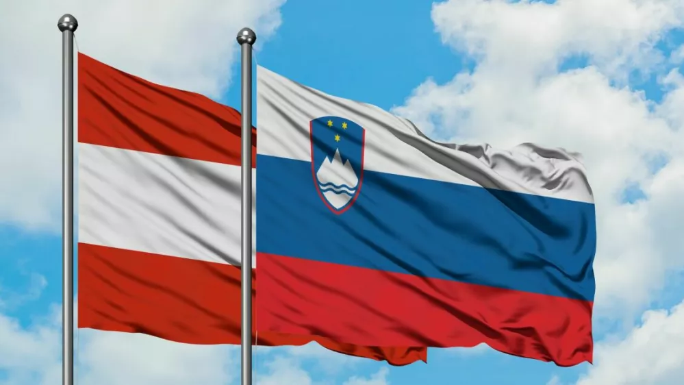﻿Austria and Slovenia flag waving in the wind against white cloudy blue sky together. Diplomacy concept, international relations.