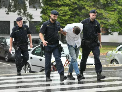 Emanuel Rep v spremstvu policistov na zaslišanje v Varaždinu. Sumijo ga umora mame s sekiro ter poskusa umorov polbrata in očima. 