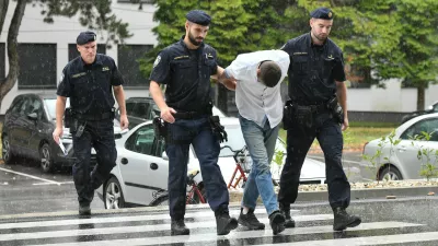 Emanuel Rep v spremstvu policistov na zaslišanje v Varaždinu. Sumijo ga umora mame s sekiro ter poskusa umorov polbrata in očima. 