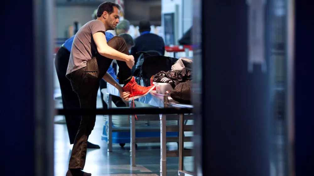 FILE PHOTO: A traveler removes his shoes before going through a security check point at John F. Kennedy Airport in New York, February, 29, 2012.  REUTERS/Andrew Burton/File Photo