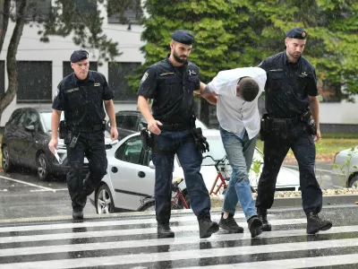 Emanuel Rep v spremstvu policistov na zaslišanje v Varaždinu. Sumijo ga umora mame s sekiro ter poskusa umorov polbrata in očima. 