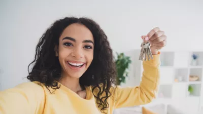 Selfie photo of smiling american happy young girl own her first apartment holding keys relocate to new house indoors loft living room. / Foto: Deagreez