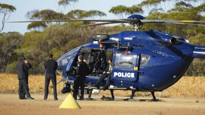 Police wait by a helicopter in Beacon, Western Australia, Friday, July 11, 2025, as they prepare to search for missing German backpacker Carolina Wilga. (ABC News via AP)