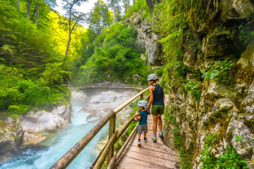 Mother and child walking on wooden path exploring vintgar gorge near bled, enjoying summer vacation in beautiful nature of slovenia