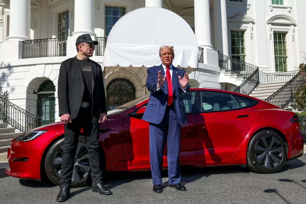 FILE PHOTO: U.S. President Donald Trump talks to the media next to Tesla CEO Elon Musk, with a Tesla car in the background, at the White House in Washington, D.C., U.S., March 11, 2025. REUTERS/Kevin Lamarque/File Photo