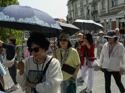 11.06.2025. Azijski turisti s senčniki v Ljubljani. Vročinski val. Foto: Bojan Velikonja 