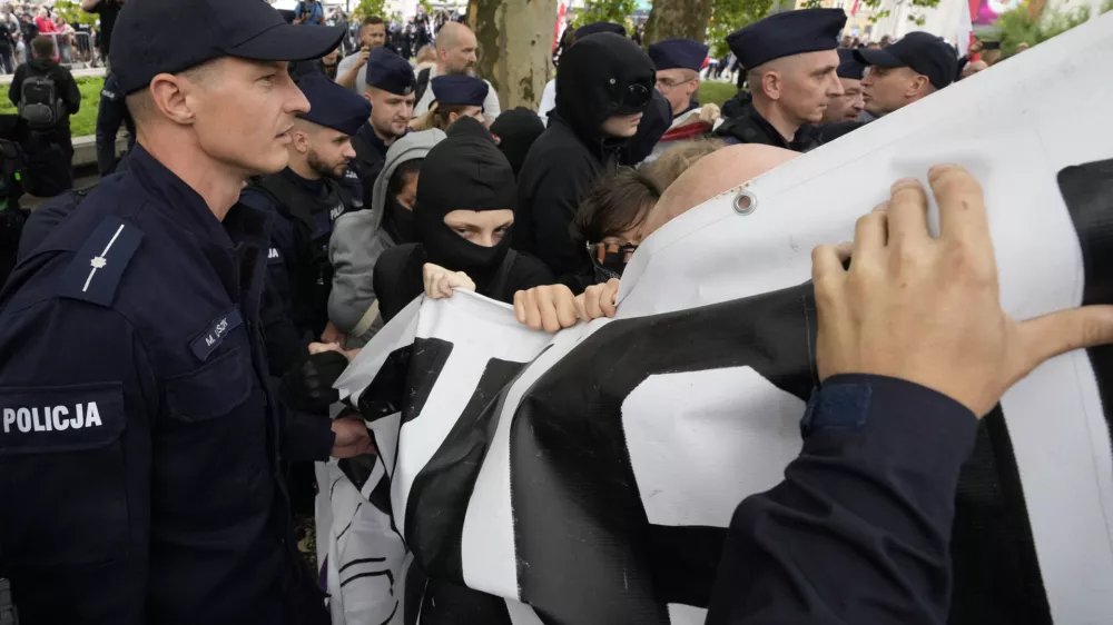 Police officers try to separate and secure a small group of counter-demonstrators who attempt to block the anti-immigration demonstration Confederation party and soccer hooligans in Warsaw, Poland, Saturday, July 19, 2025. (AP Photo/Czarek Sokolowski)