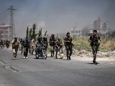 19 July 2025, Syria, As Suwayda: Bedouin and tribal fighters gather in the city of As-Suwayda, as smoke rises from burning houses amid clashes between tribal fighters and local Druze factions in southern Syria. Fear and shock grip the province following the escalation of isolated clashes into one of the deadliest outbreaks of violence the region has seen in years. Photo: Moawia Atrash/dpa