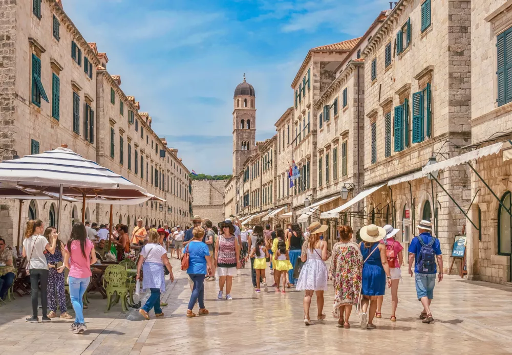 Dubrovnik, Croatia - June 3, 2016. Showing Dubrovnik's main street, the Stradun, which is lined with shops and crowded with summer tourists. The buildings and street are made of limestone. In the background is the Old Town's bell tower.