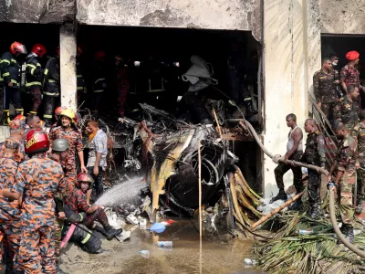 Firefighters and army members work next to the wreckage of an air force training aircraft after it crashed into Milestone College campus, in Dhaka, Bangladesh, July 21, 2025. REUTERS/Stringer