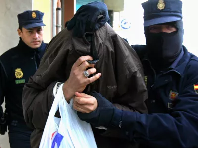 Police lead a man under arrest out of a building in Malaga, Spain, Monday Dec. 19. 2005. Spanish police arrested 14 people Monday on suspicion of recruiting and indoctrinating fighters for Iraq's insurgency. More than 100 police officers staged raids that led to the arrests in the regions of Catalonia and Andalusia as well as in Spain's Balaearic Islands, a police official said. (AP Photo)