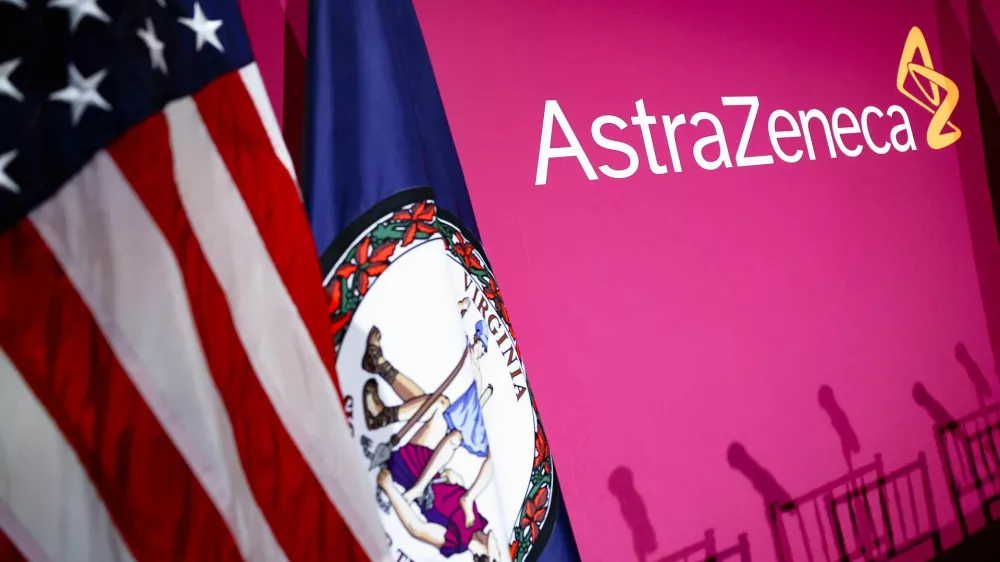 The flags of the U.S. and the state of Virginia stand next to the AstraZeneca logo during a signing event for documents related to a manufacturing site investment at the Meridian International Center in Washington, D.C., July 21, 2025. REUTERS/Umit Bektas