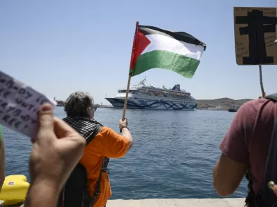 A protester waves a Palestinian flag as people demonstrates in front of a cruise ship carrying Israeli tourists and trying to approach the Aegean Sea island of Syros, Greece, Tuesday, July 22, 2025. (Nikos Panagiotopoulos/InTime News via AP)