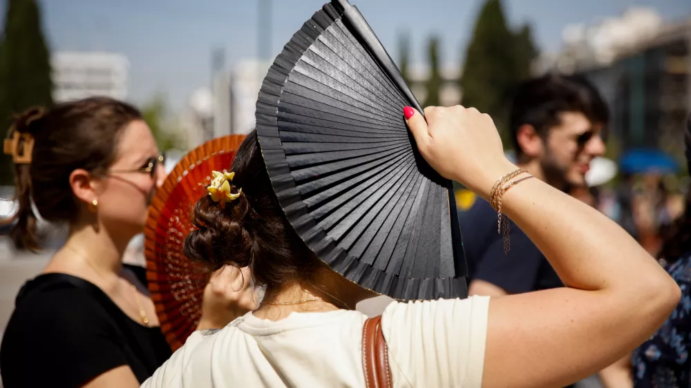 23 July 2025, Greece, Athen: Tourists stand in front of the Greek parliament in the center of Athens. A heatwave with temperatures of over 40 degrees is making life difficult for people in large parts of Greece. Photo: Socrates Baltagiannis/dpa