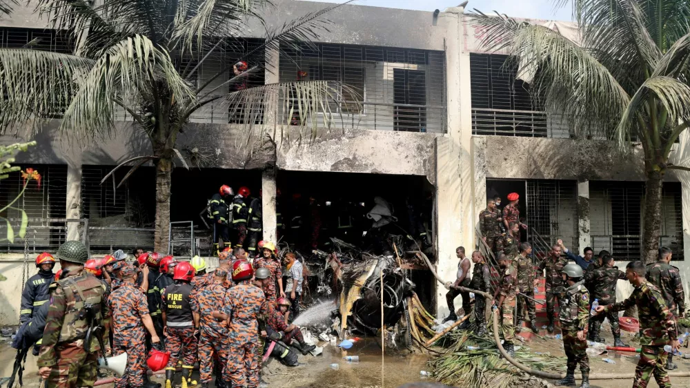 FILE PHOTO: Firefighters and soldiers work next to the wreckage of an air force training aircraft after it crashed into Milestone College campus, in Dhaka, Bangladesh, July 21, 2025. REUTERS/Stringer/File Photo