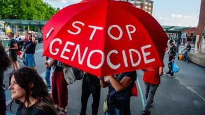 24 July 2025, Netherlands, Nijmegen: A protester holds a red umbrella with the message "Stop the genocide" during a pro-Palestine rally. Outside the train station, people gathered and made loud noises with pots and instruments to call for an end to the famine in Gaza. Photo: Ana Fernandez/SOPA Images via ZUMA Press Wire/dpa