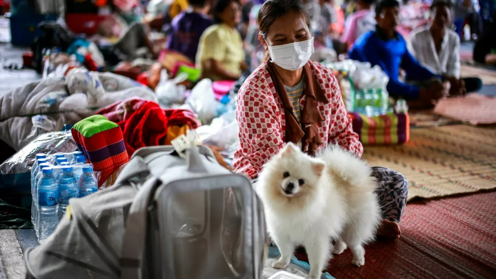 Juam, 50 sits next to her dog "Krati" inside a temporary shelter in Srisaket province, after Thailand and Cambodia exchanged heavy artillery fire for a second day on Friday as border fighting intensified and spread, while Cambodia's leader said Thailand had agreed to a Malaysian ceasefire proposal but then backed down, Thailand, July 26, 2025. REUTERS/Athit Perawongmetha