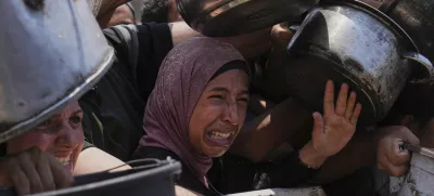 Palestinians struggle to get donated food at a community kitchen, in Gaza City, northern Gaza Strip, Saturday, July 26, 2025. (AP Photo/Abdel Kareem Hana)
